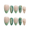 Product display of short almond press-on nails in nude and green shades with tropical leaf patterns and golden touches