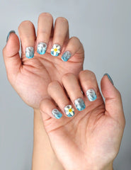 Side view of minimalist blue press-on nails in squoval shape with hand-painted white blossoms