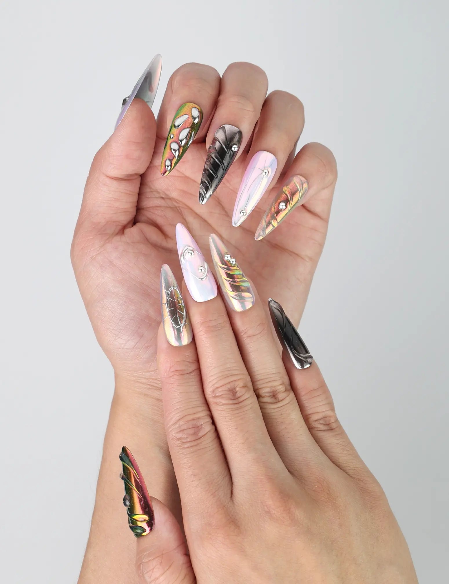 Fingers fanned out to show off multicolor chrome stiletto nails with shimmering gem detailing by Naillover