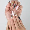 Fingers fanned out to show off multicolor chrome stiletto nails with shimmering gem detailing by Naillover