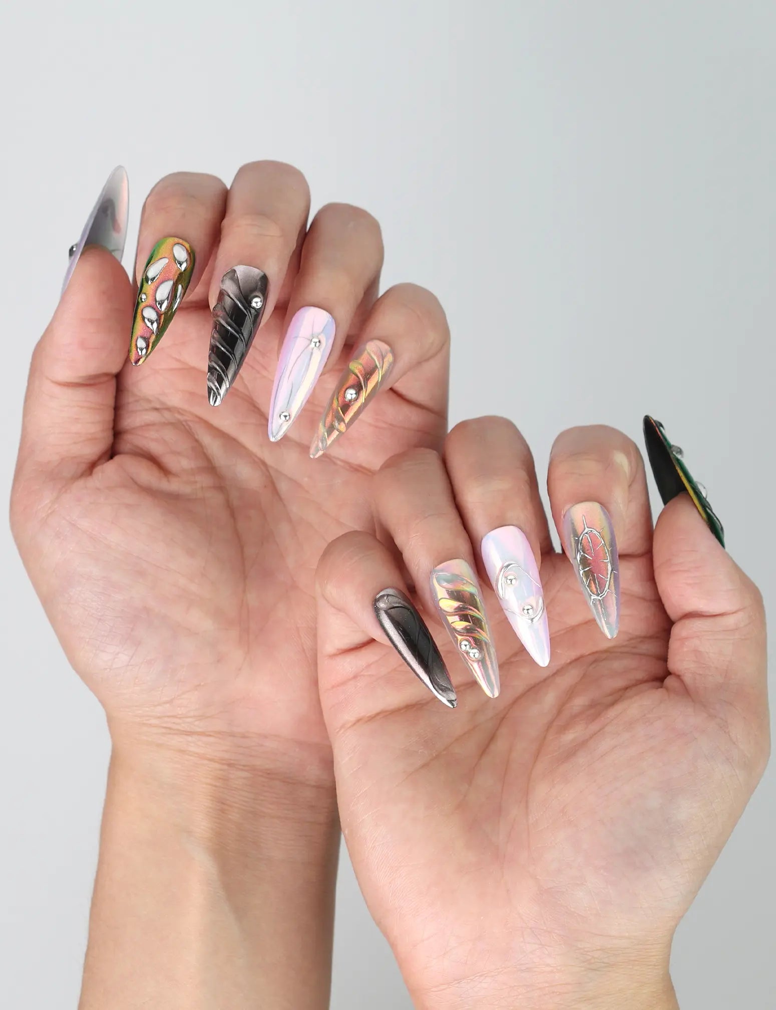 Stylish hand pose highlighting the iridescent chrome glow and embedded gems on stiletto press on nails by Naillover