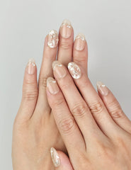 Ivory Bloom press on nails worn on hand, showing nude base with gold leaf and floral design, NailLover Singapore.