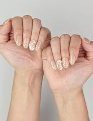 Elegant Ivory Bloom trendy nails on hand, blending nude tones with floral art and subtle gold accents.