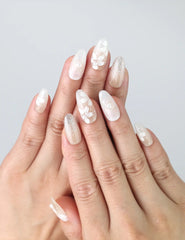 Hand gesture showing medium oval press on nails with ivory base, 3D floral details, and pearl accents by Naillover