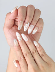 Close-up of handmade ivory press on nails with elegant 3D flowers and pearls in a soft oval shape by Naillover