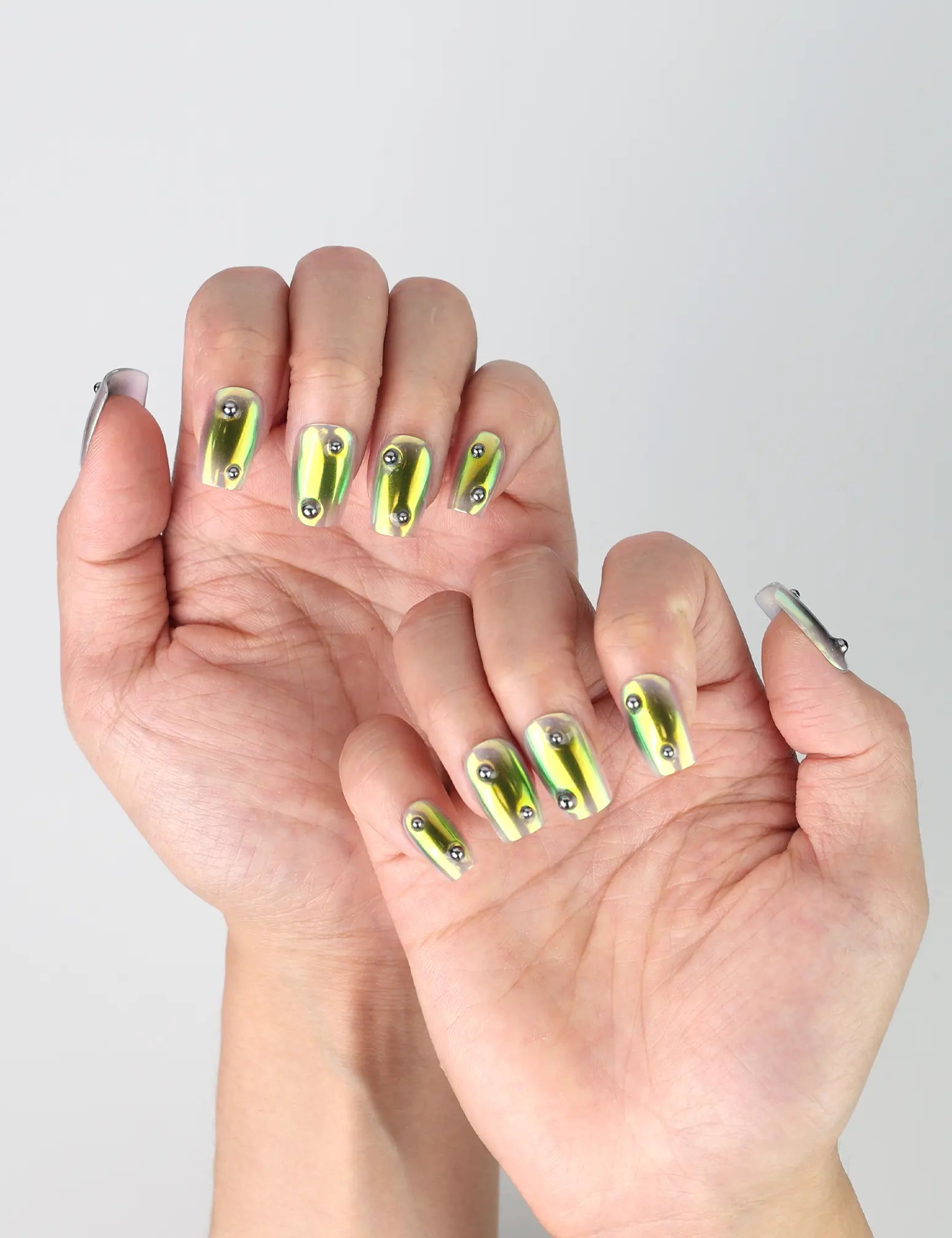 Side view of handmade short green square press-on nails with shimmering chrome surface and deep green luster