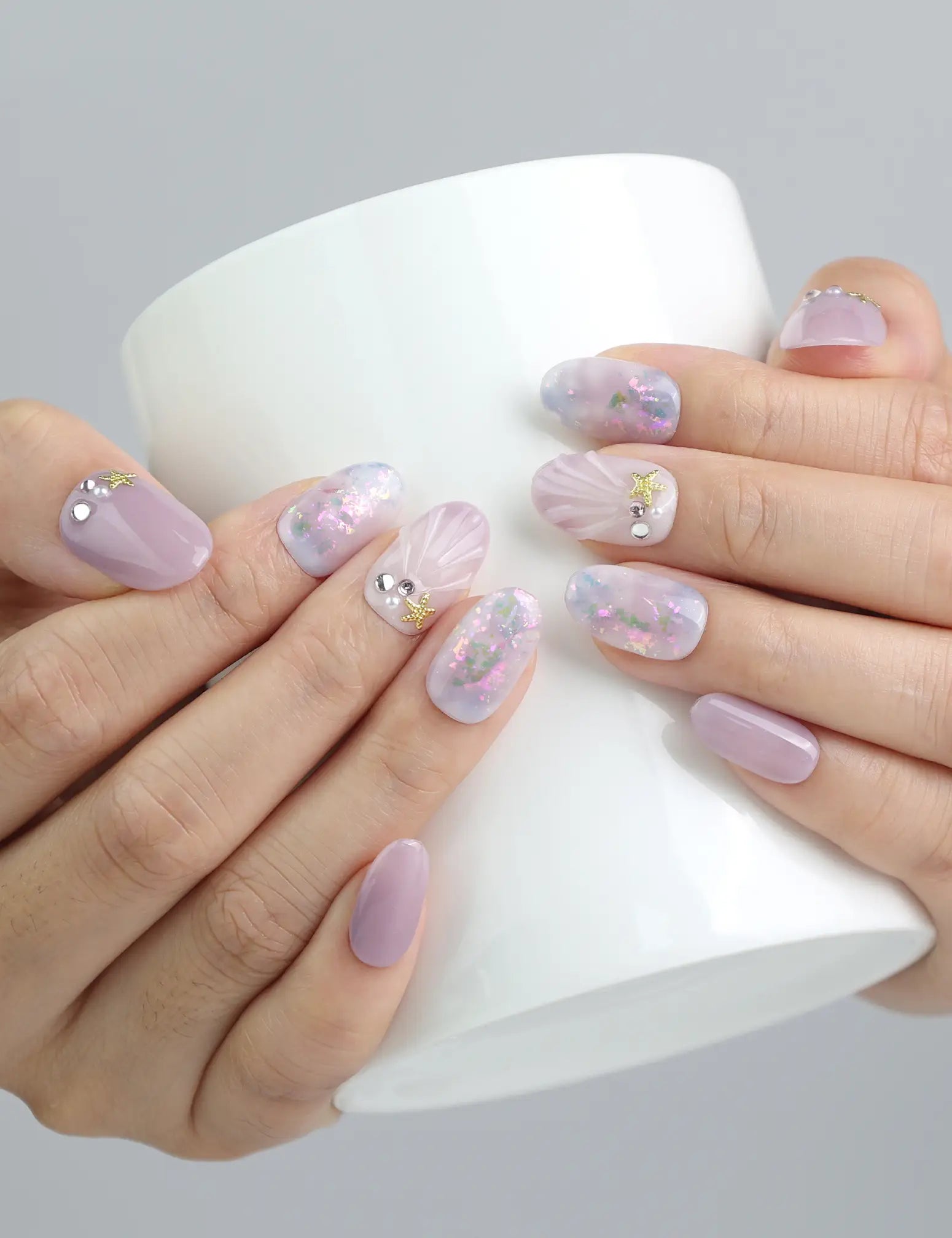Hand holding a cup, showcasing pastel lavender and pink gradient nails with holographic shine by Naillover