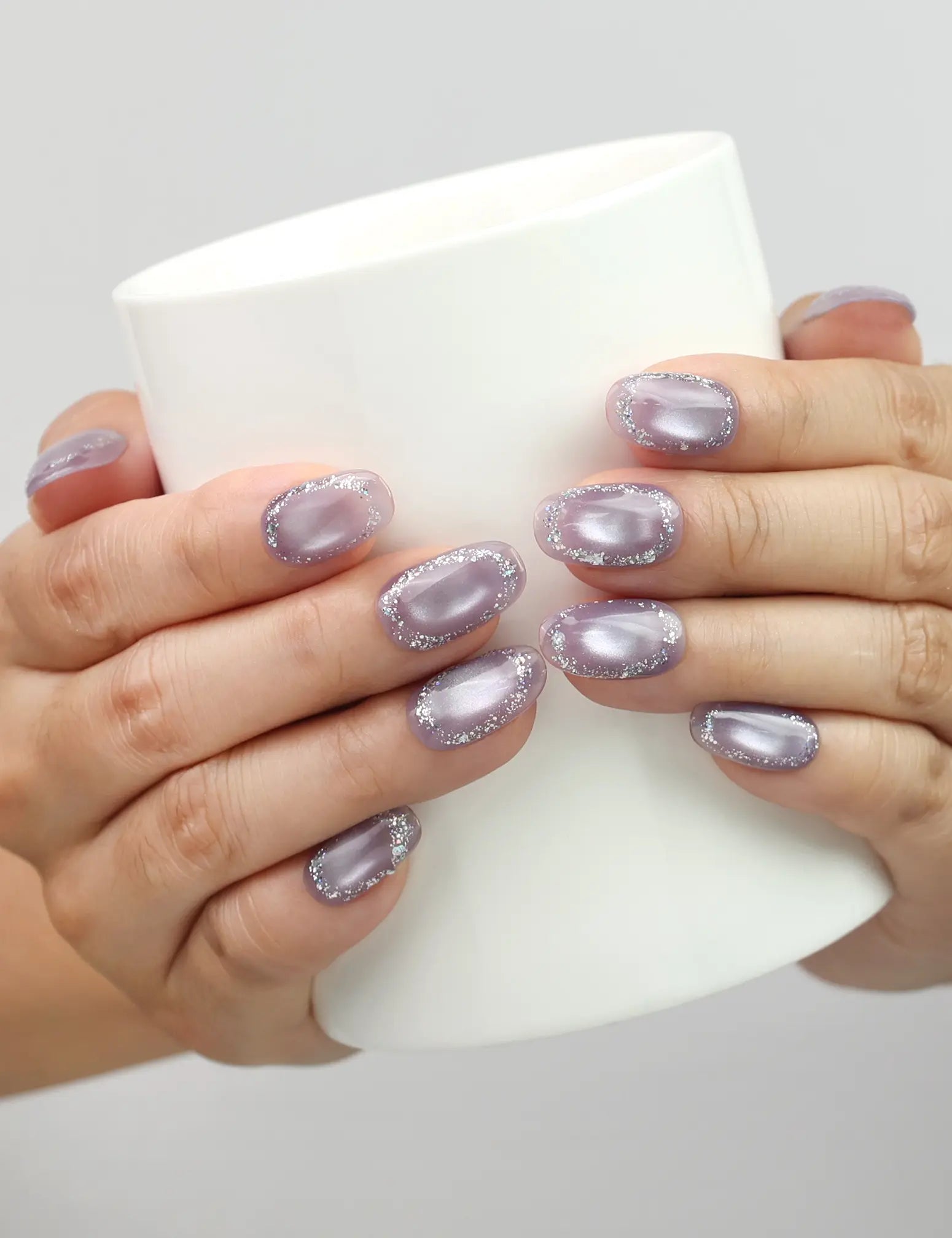 Naillover Lavender Sparkle handmade press on nails holding a glass, showing glitter lavender cat eye finish