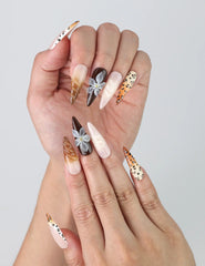 Close-up of handmade animal print press-on nails with black stiletto tips and soft pink flower details