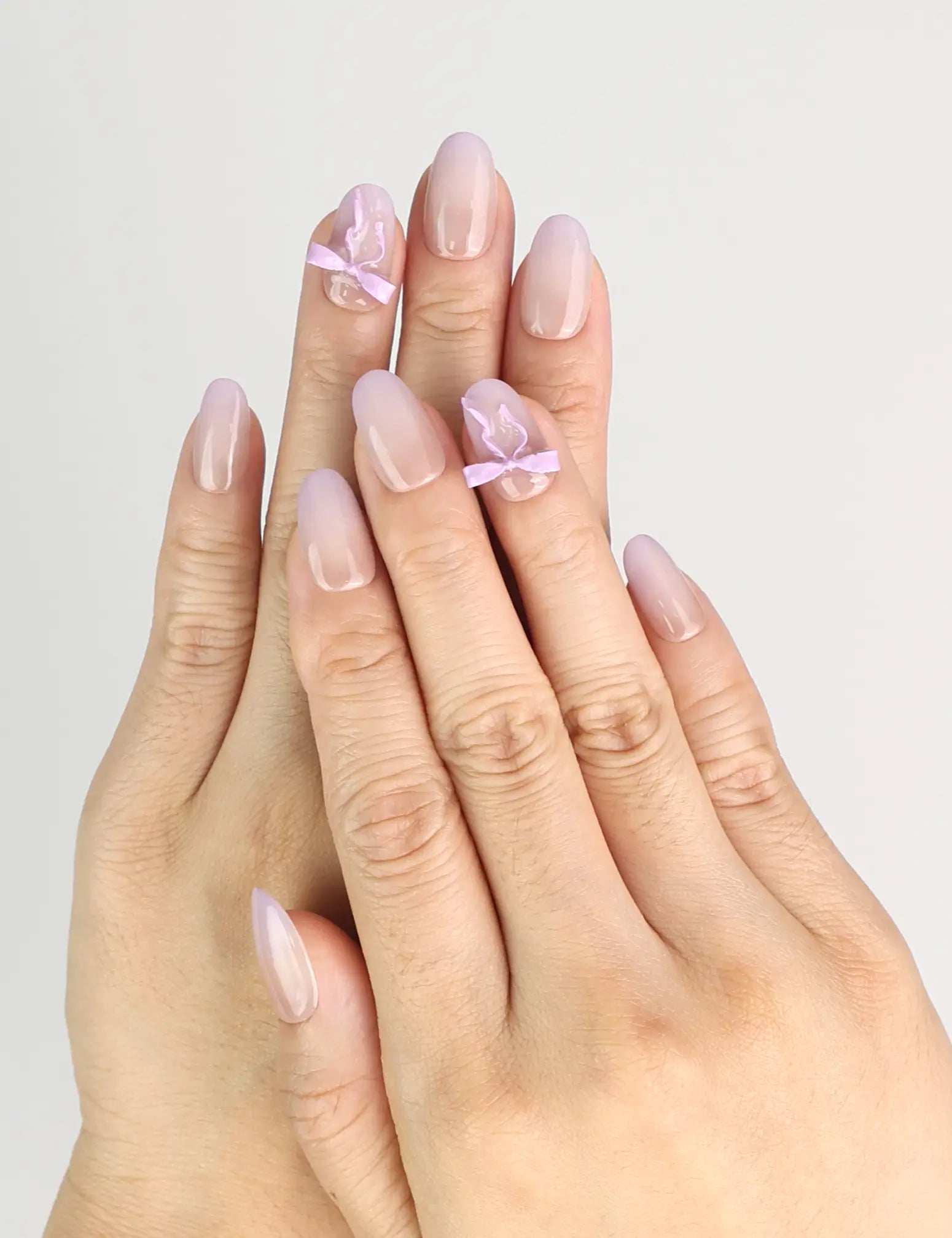 Hand wearing Naillover Lilac Whisper Singapore press on nails with beige base and lavender ribbon accents
