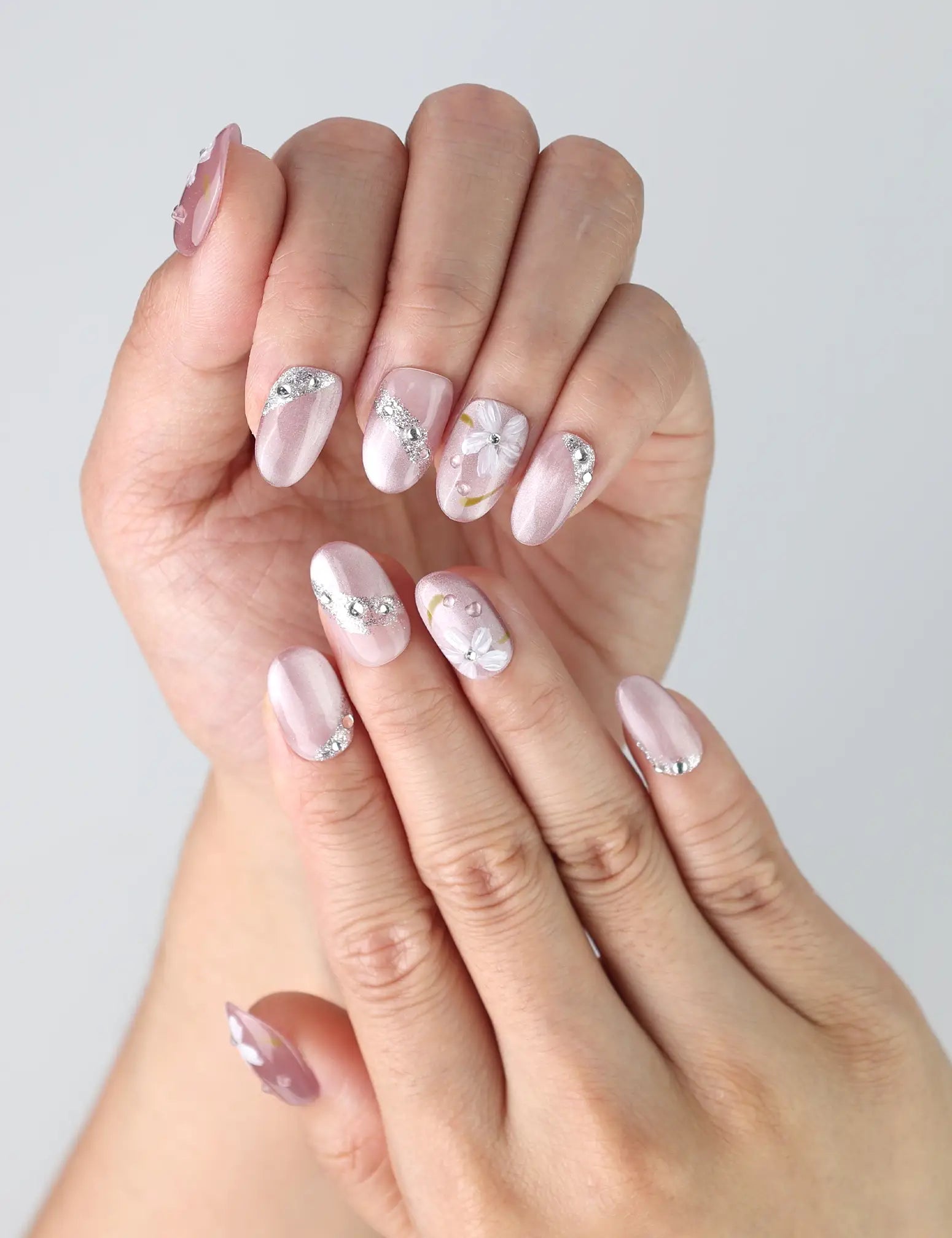 Fingers shown wearing Singapore handmade pink nails adorned with subtle flower art and sparkling rhinestones