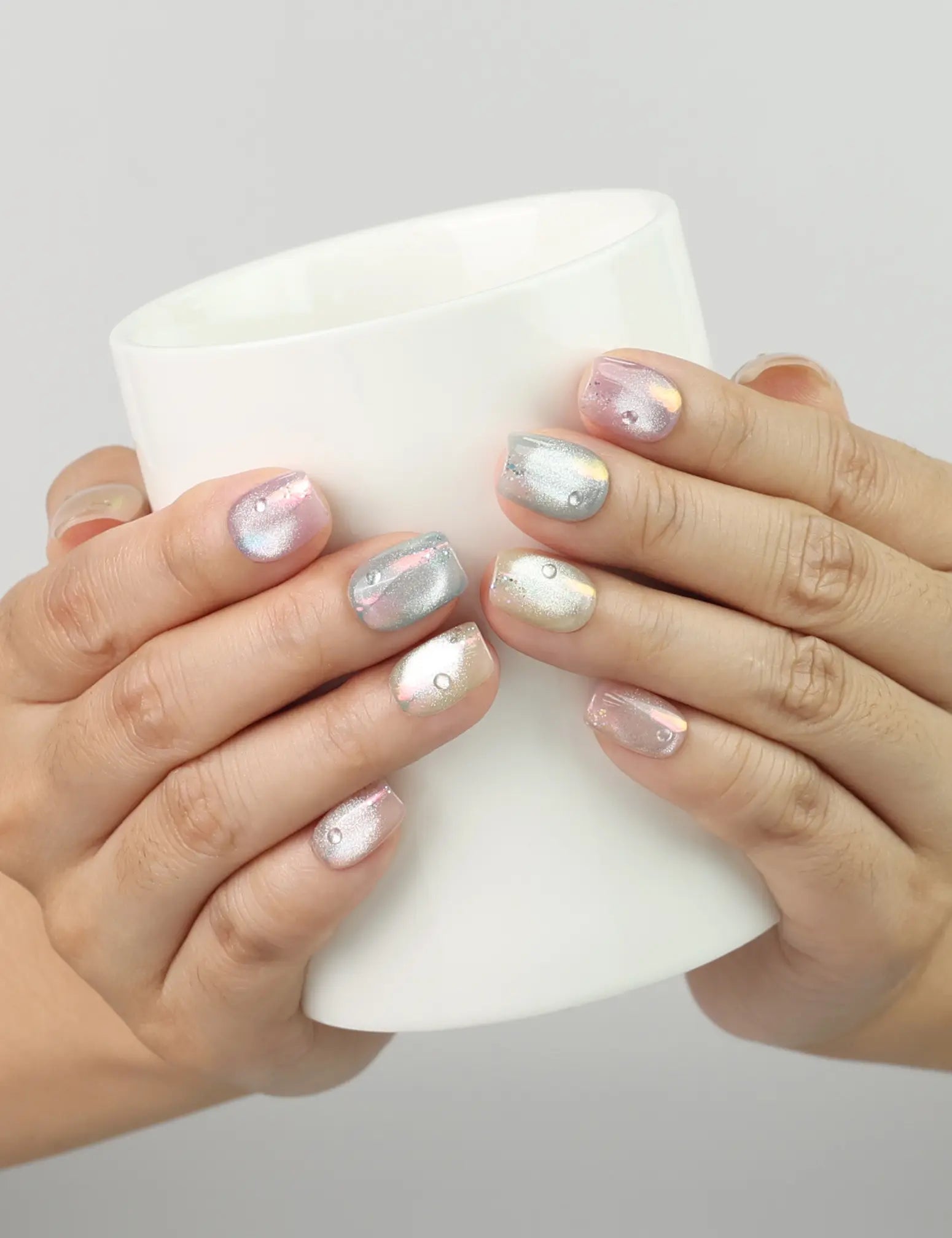 Hand holding a glass, showing Mermaid Glaze pastel pearl handmade press on nails from Naillover Singapore collection