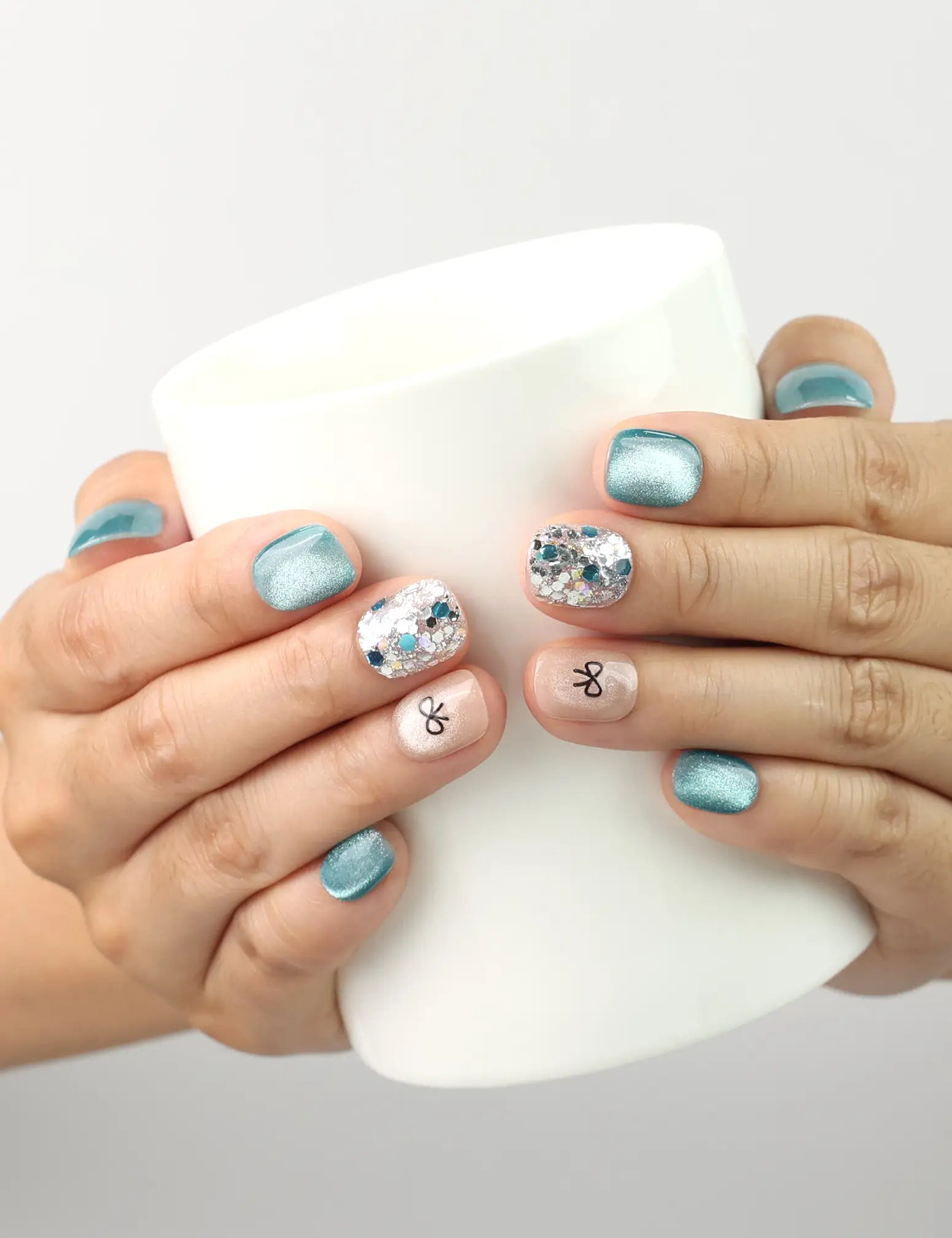 Mint Frost handmade blue shimmer press on nails with crystal accents and bow, holding coffee cup, naillover Singapore