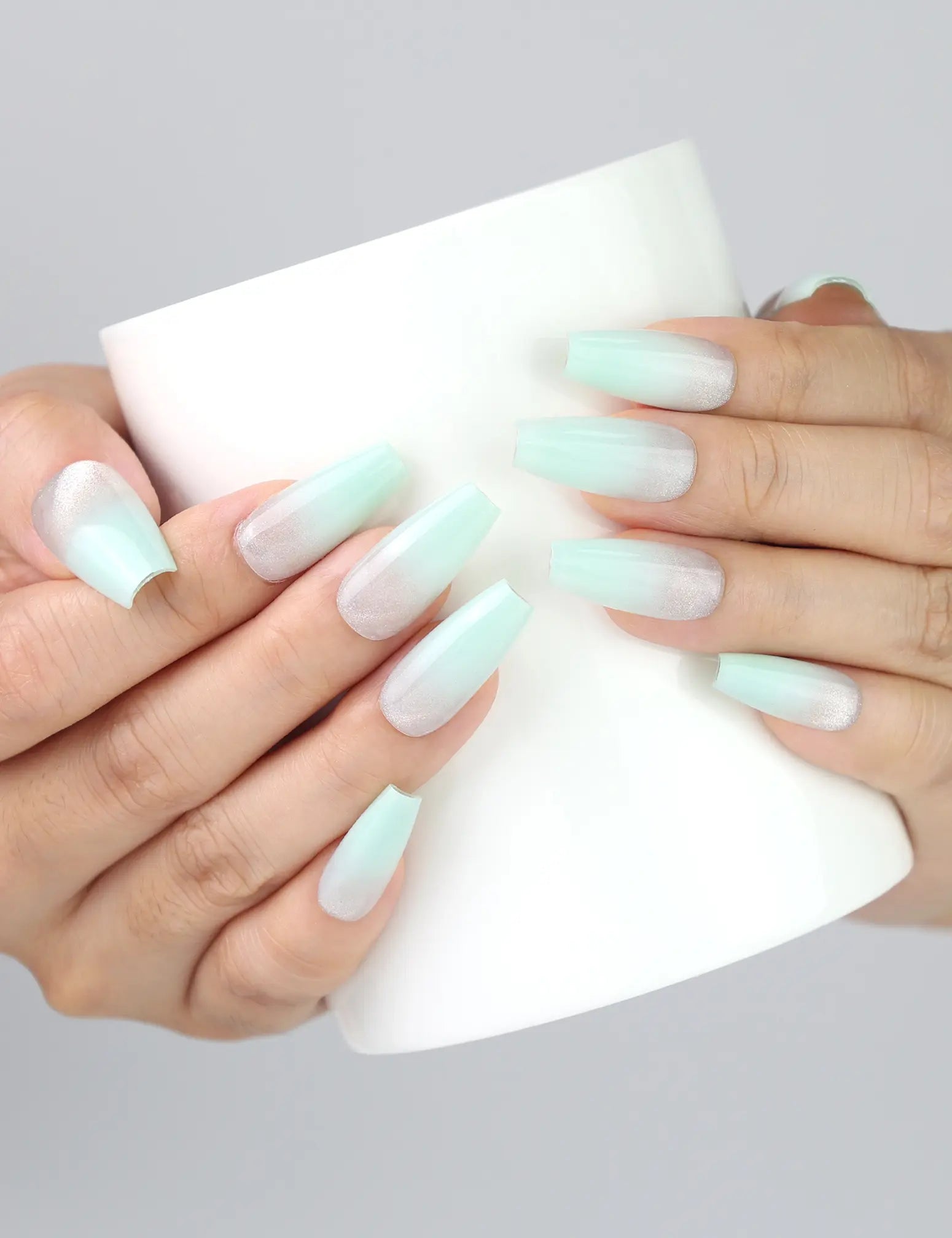 Hand holding cup while wearing Naillover Misty Blue Fade press on nails, featuring cool-toned gradient nails.