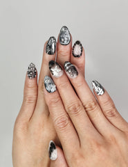 Hand wearing Naillover Moonlit Noir handmade press on nails with black and silver marble design and chrome accents.