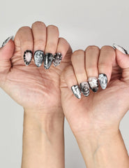 Naillover Moonlit Noir trendy nails styled on hand, highlighting bold marble textures with metallic details.