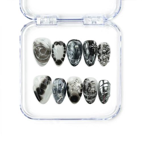 Naillover Moonlit Noir handmade press on nails featuring black and silver marble patterns, chrome swirls, studs, and star accents for a bold trendy look.
