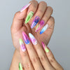 Hand model wearing almond-shaped press-on nails with bright neon flame tips on a clean white glossy background
