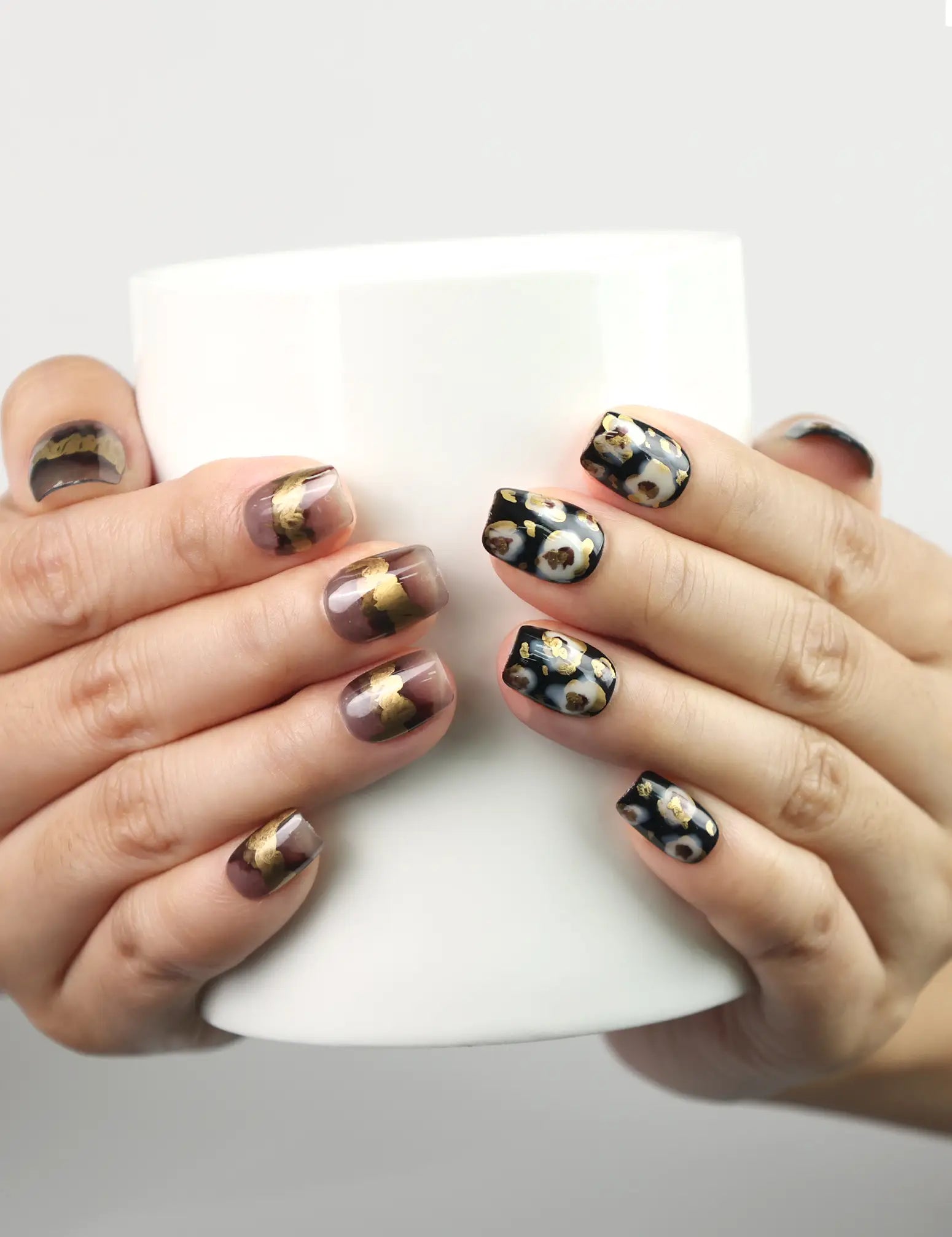 Hand holding a cup while showcasing Mystic Flow handmade press on nails with artistic swirl design and shimmering accents