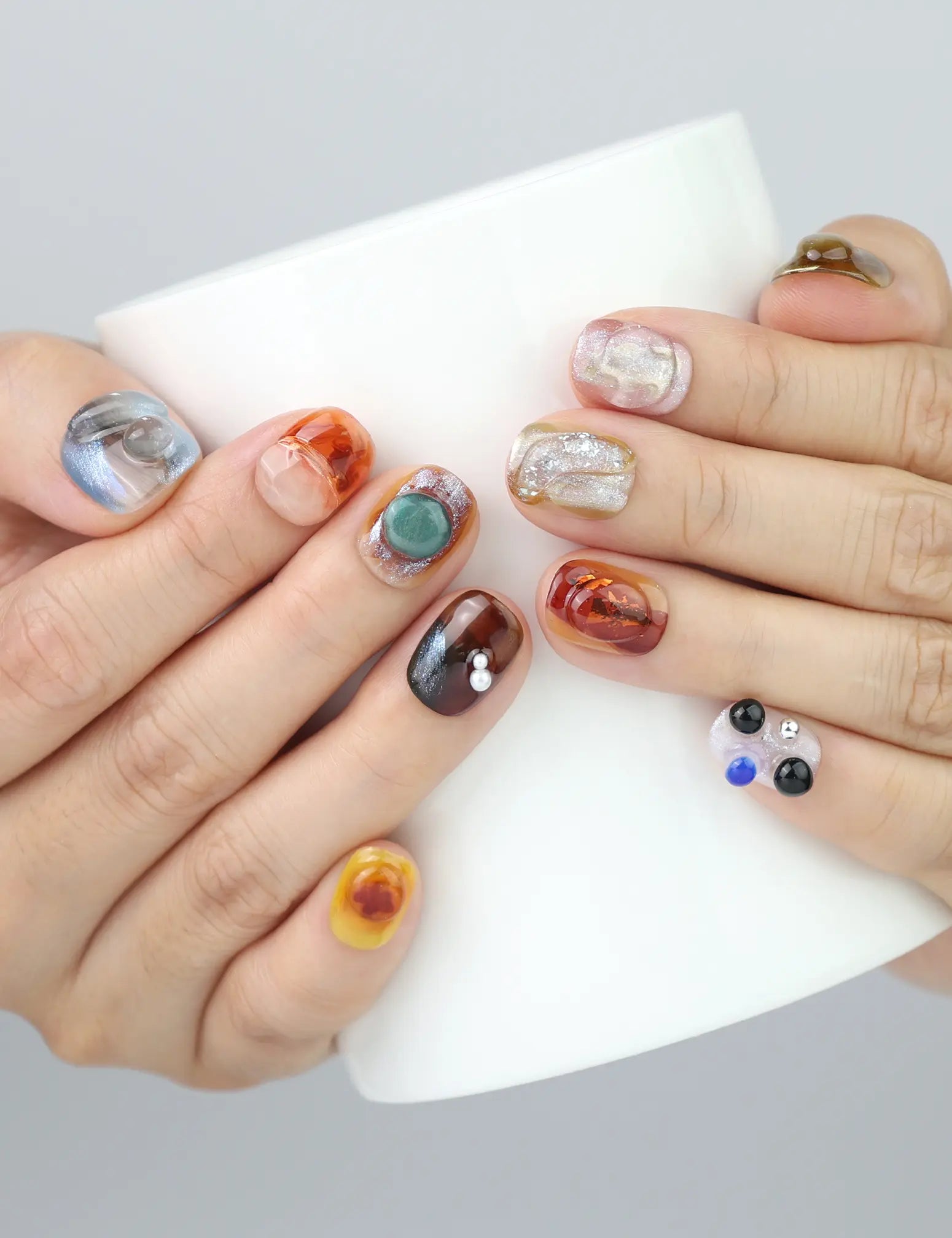 Naillover Amber Whisper nails wrapped around a ceramic mug—highlighting the earthy tones and handmade detail.