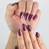 Close-up of fingers with purple handmade Amethyst press on nails glowing with cat eye shimmer.
