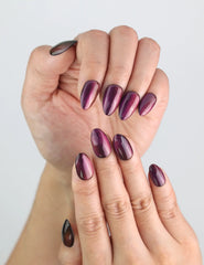 Close-up of fingers with purple handmade Amethyst press on nails glowing with cat eye shimmer.