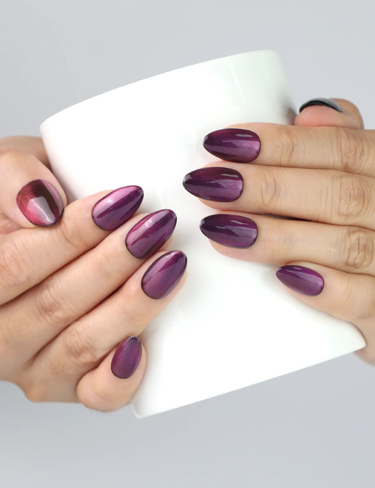 Woman holding a coffee cup while wearing Amethyst cat eye press on nails by Naillover.