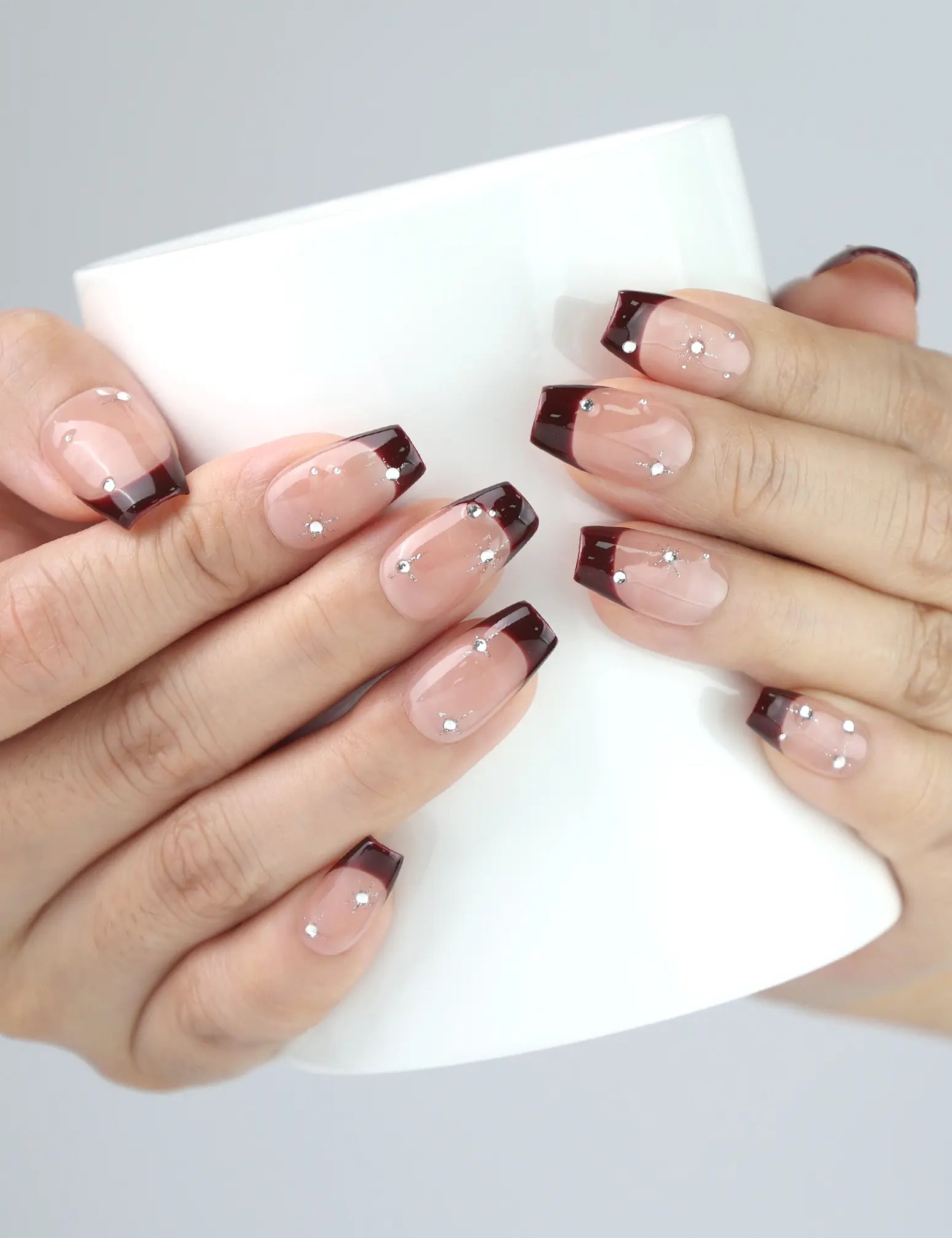 Hand holding a coffee cup with Naillover Bare Crystal handmade nails — clear and amber press on nails, stylish yet understated.