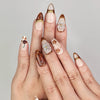 Hand wearing Naillover Blossom Latte Singapore press on nails with beige base, brown floral patterns, and gold accents