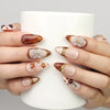 Hand holding a cup while wearing Naillover Blossom Latte Singapore press on nails, showcasing handmade beige nails with floral and gold details