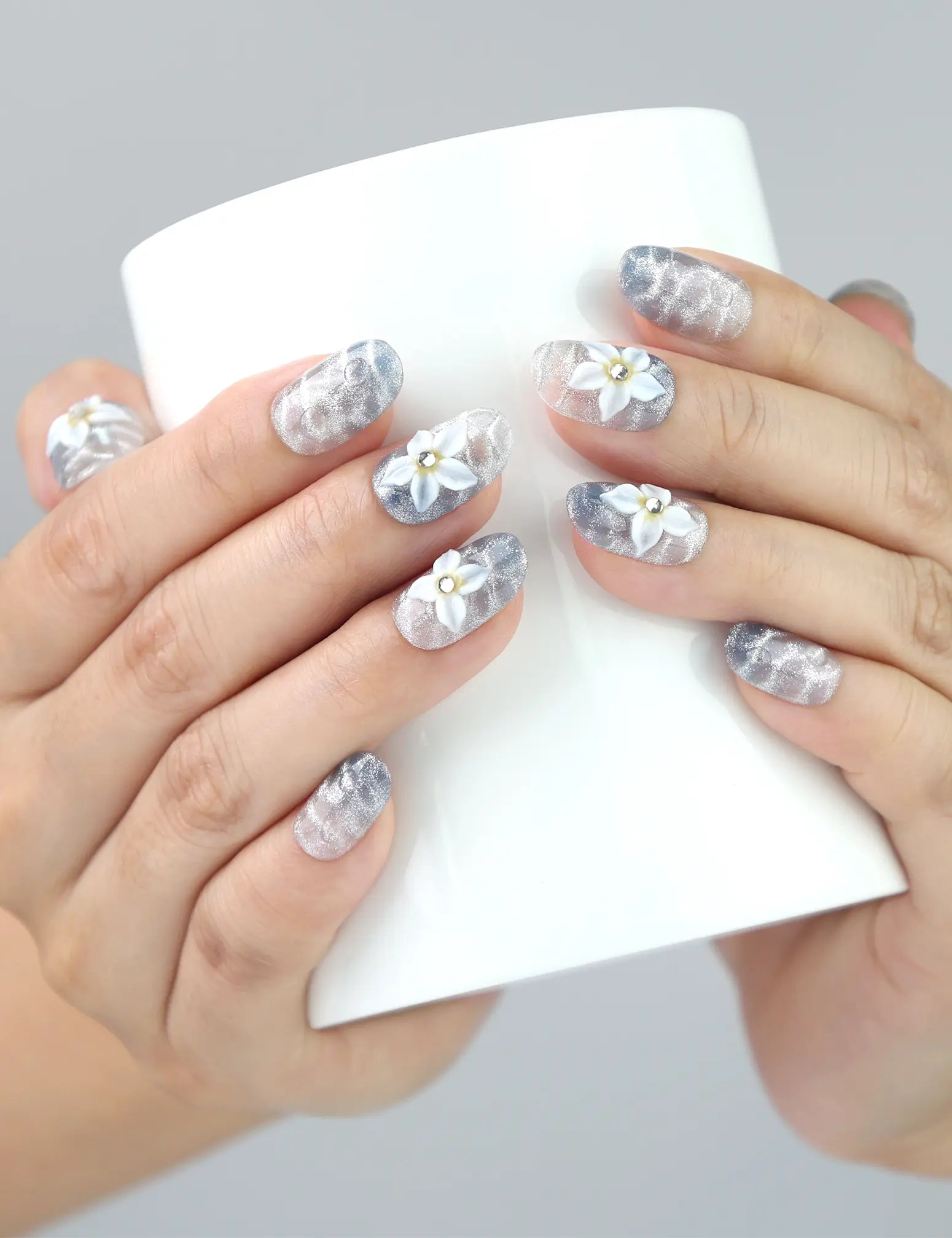 Naillover Blue Blossom nails wrapped around a cup—chic handmade press on nails in pastel blue with beachy floral accents.
