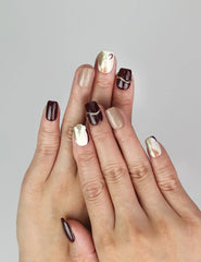 Model wearing Naillover Burgundy Wave handmade Singapore press on nails in burgundy, white, and nude with gold accents.