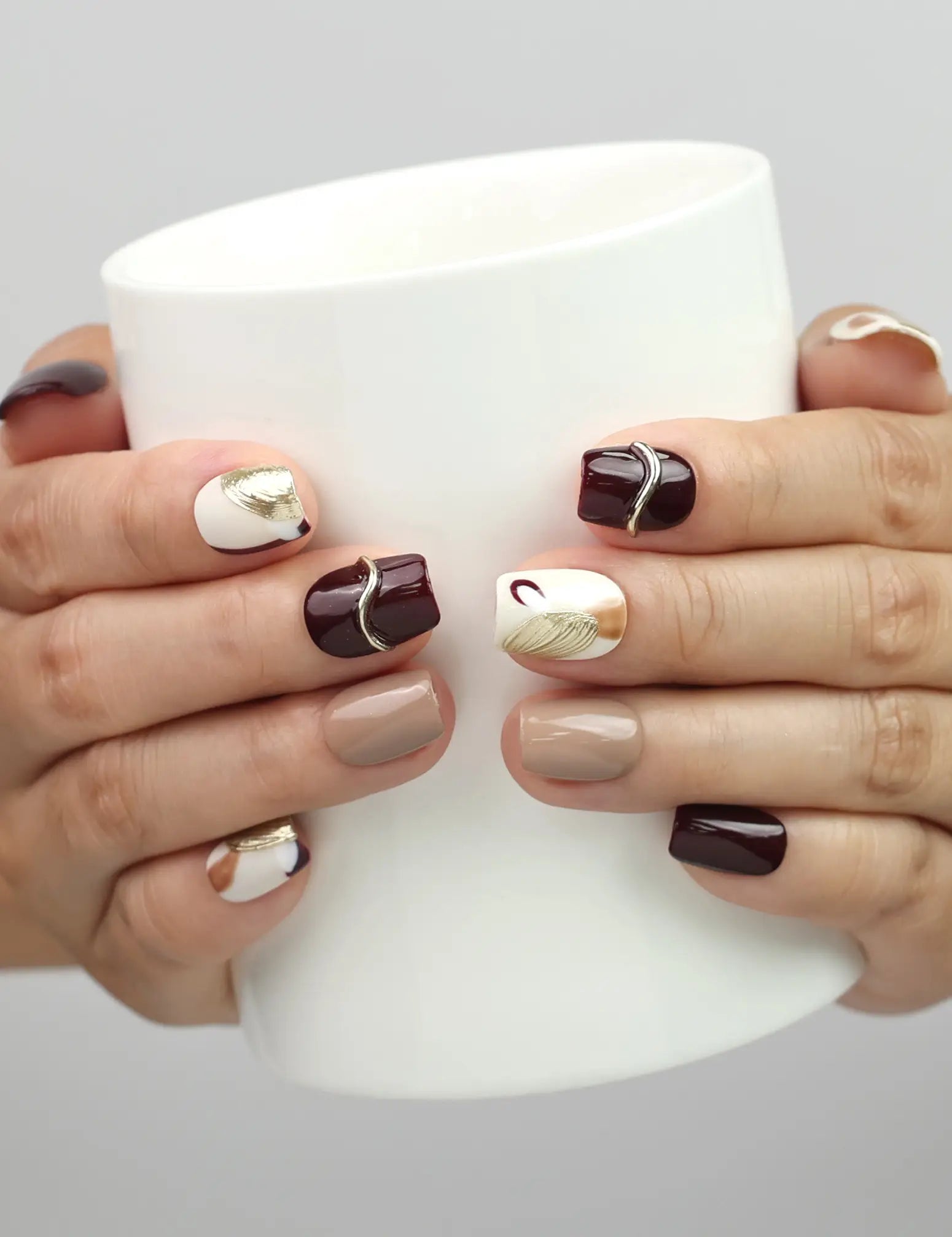 Model holding a cup while wearing Naillover Burgundy Wave handmade Singapore press on nails in chic burgundy tones.