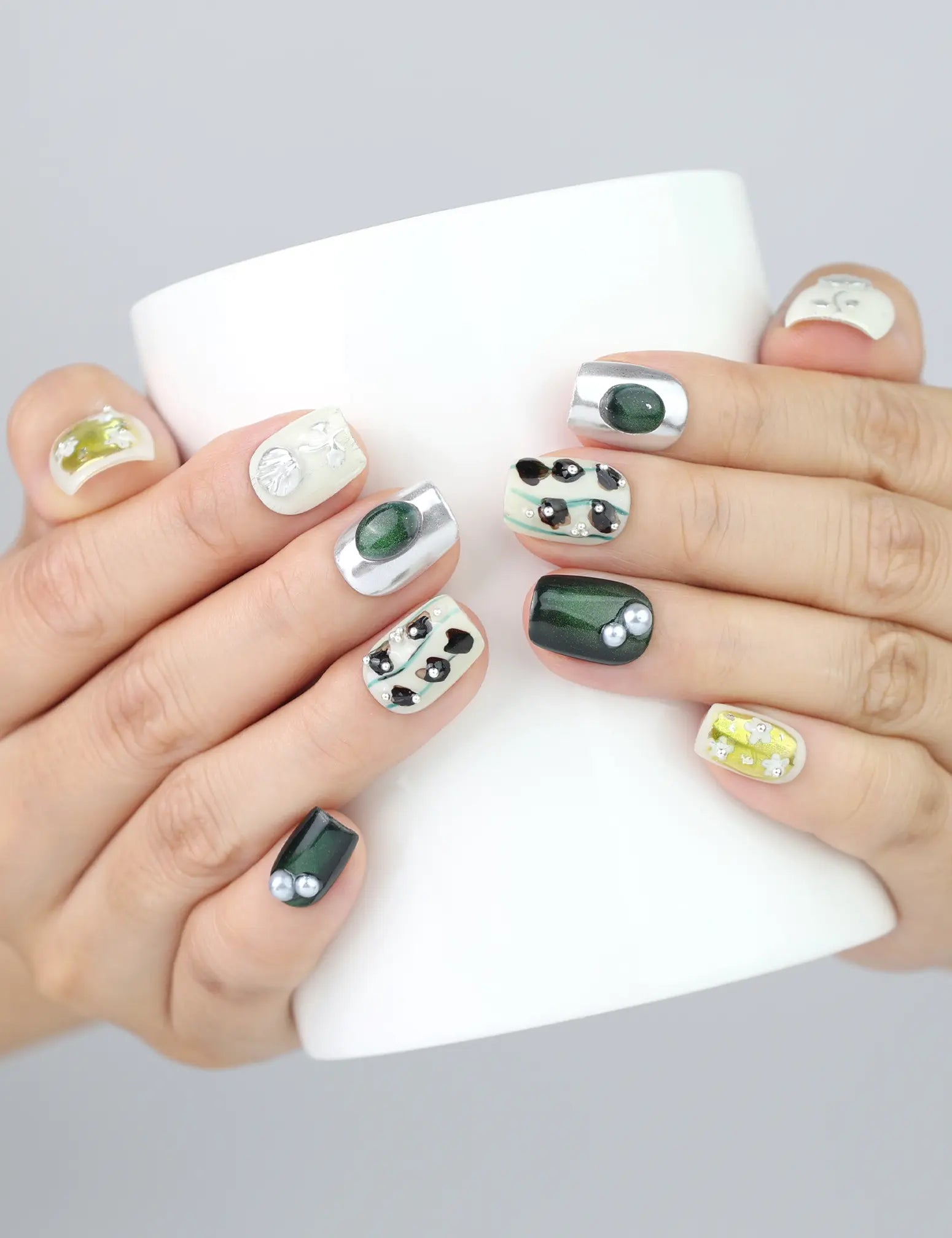 Hand holding a mug with Naillover Chic Contrast nails, highlighting bold color and delicate floral textures.