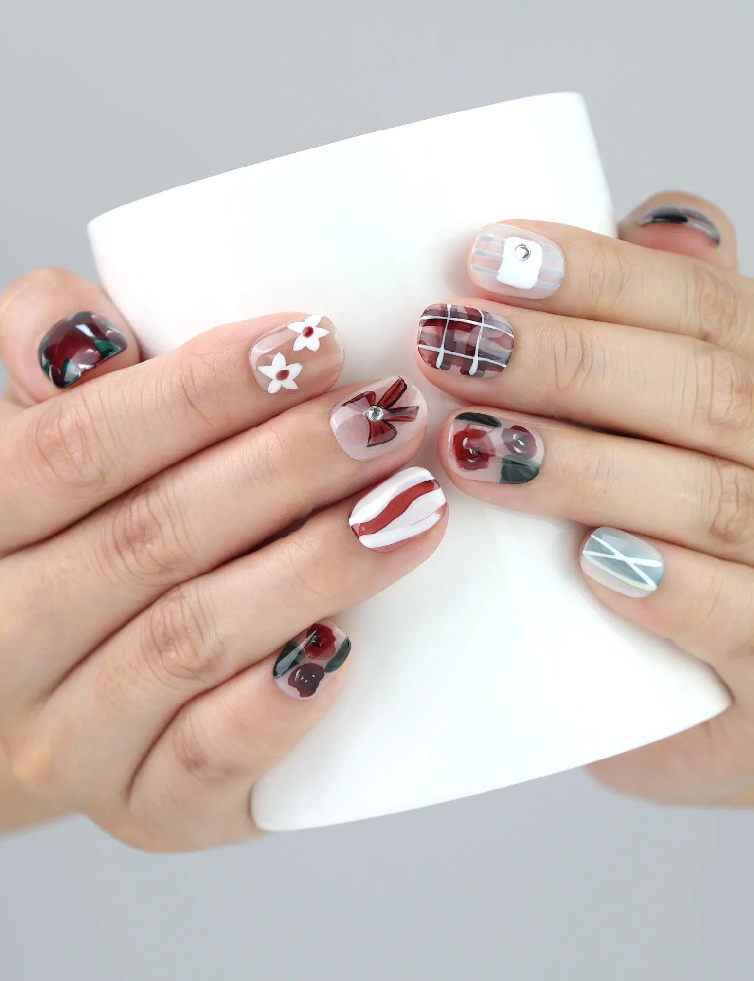 Hand gripping coffee cup wearing Naillover Chocolate Plaid nails—floral press on nails with plaid pattern and bow details from Singapore.