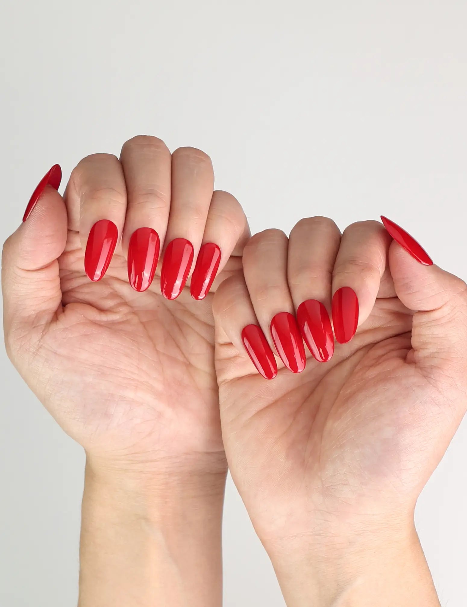 Model showcasing glossy ruby red medium oval handmade Singapore press on nails by Naillover for a bold yet refined look