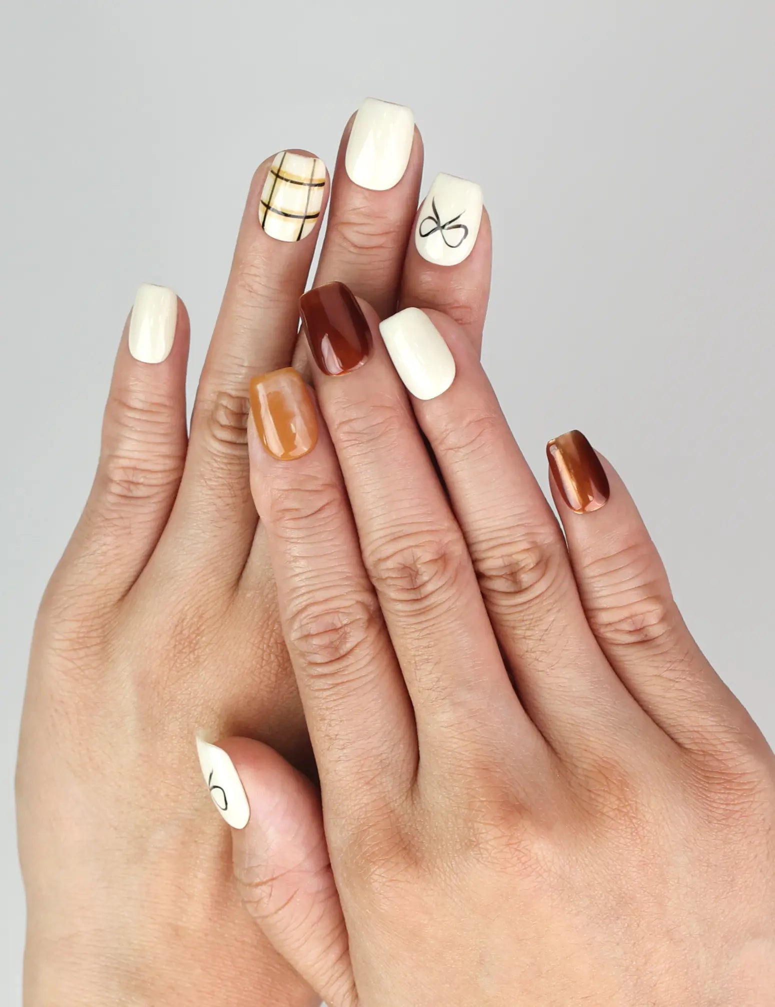 Model wearing Naillover Cocoa Grid handmade press on nails, showcasing creamy white and brown minimalist nail design.