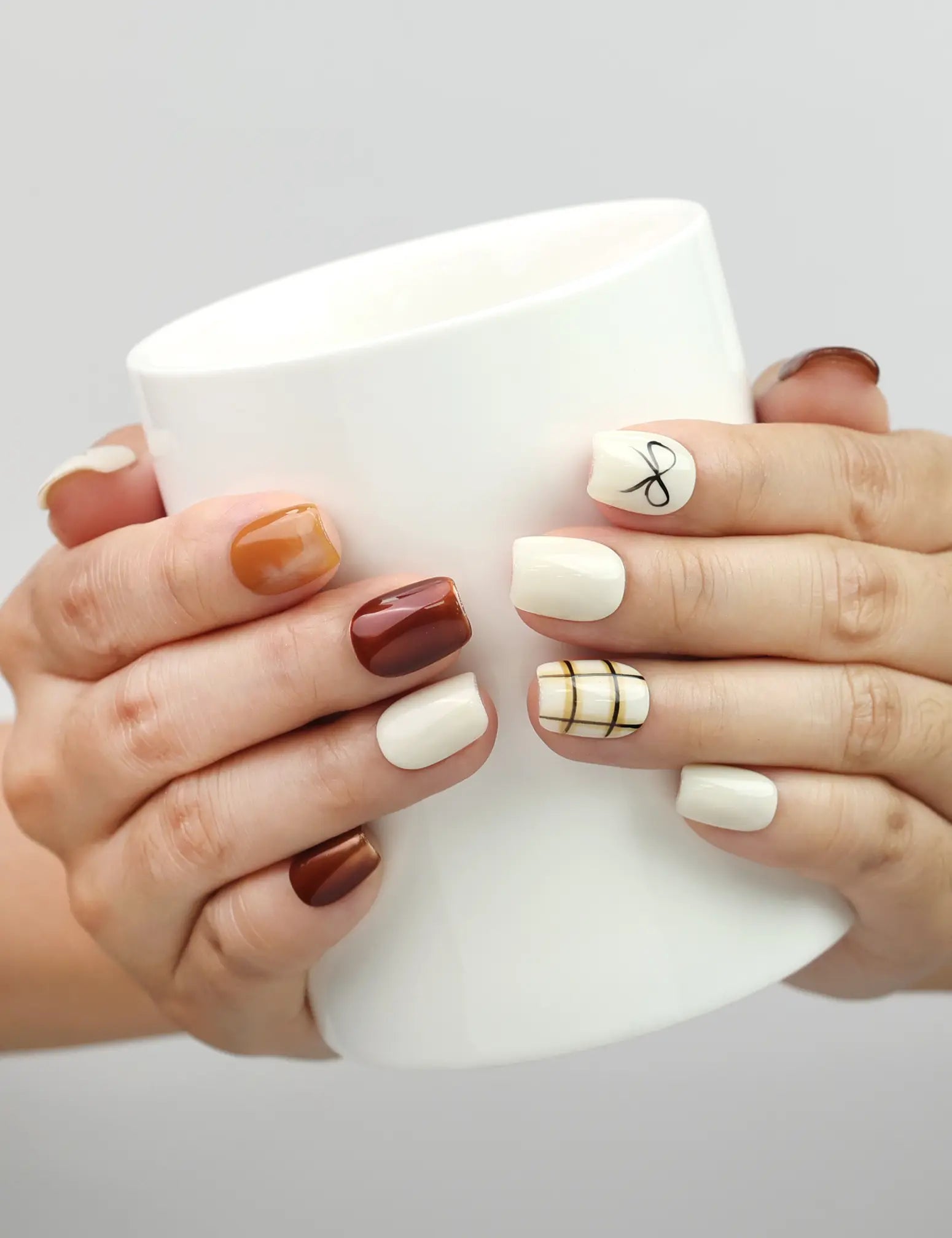 Hand holding a cup while wearing Naillover Cocoa Grid handmade press on nails, perfect for everyday chic style.