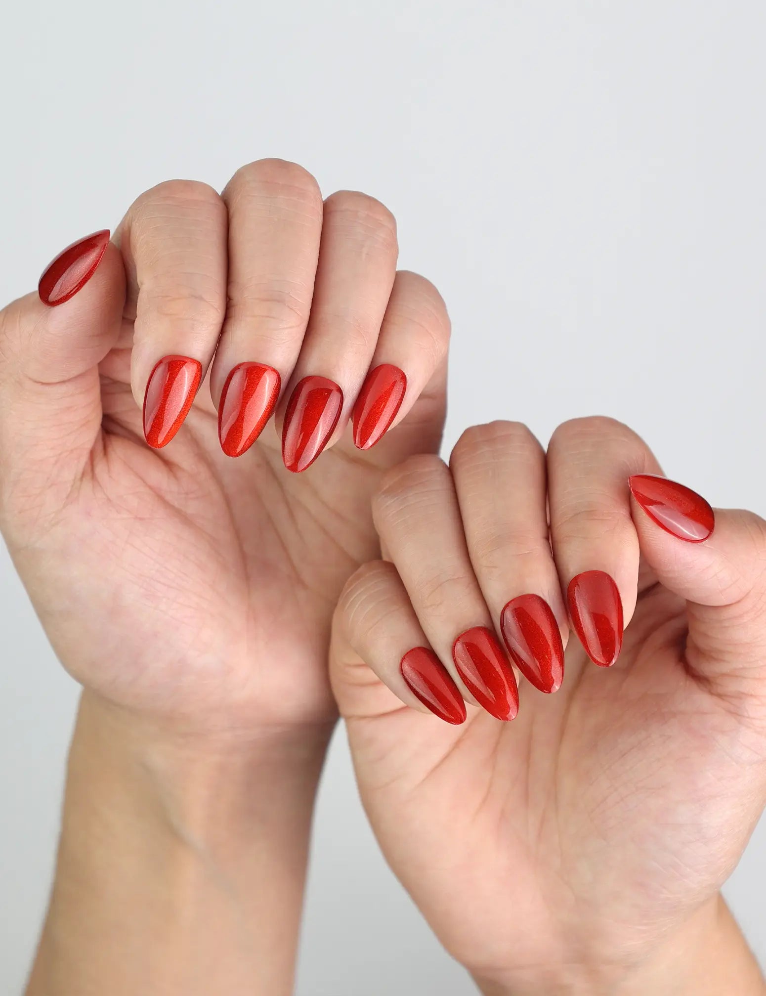 Angled view of fingers with Naillover Crimson Magnet nails, highlighting rich red tones and glossy cat-eye finish.