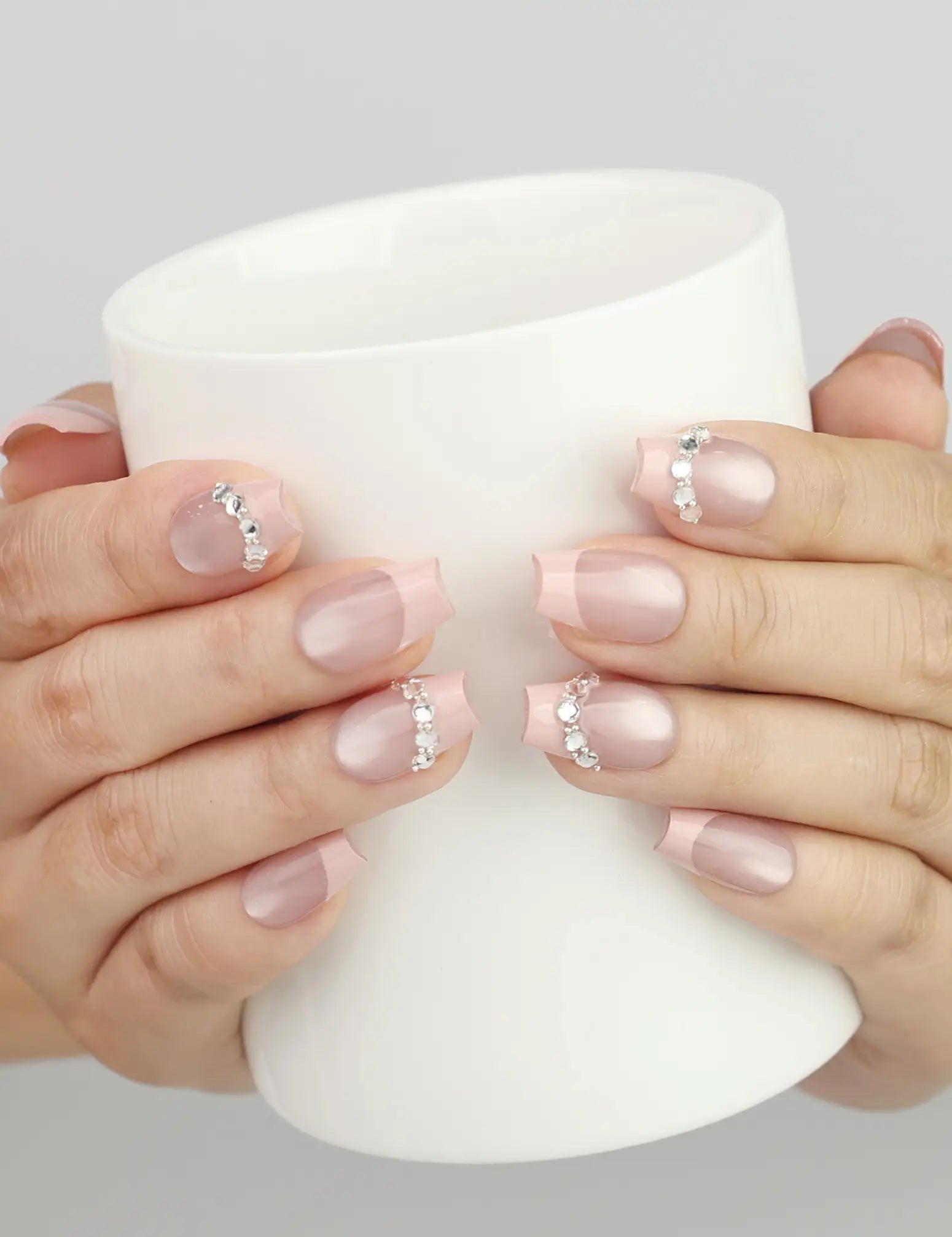 Hand holding a cup with Naillover Crystal Crescent Singapore press on nails with shimmering crystal accent