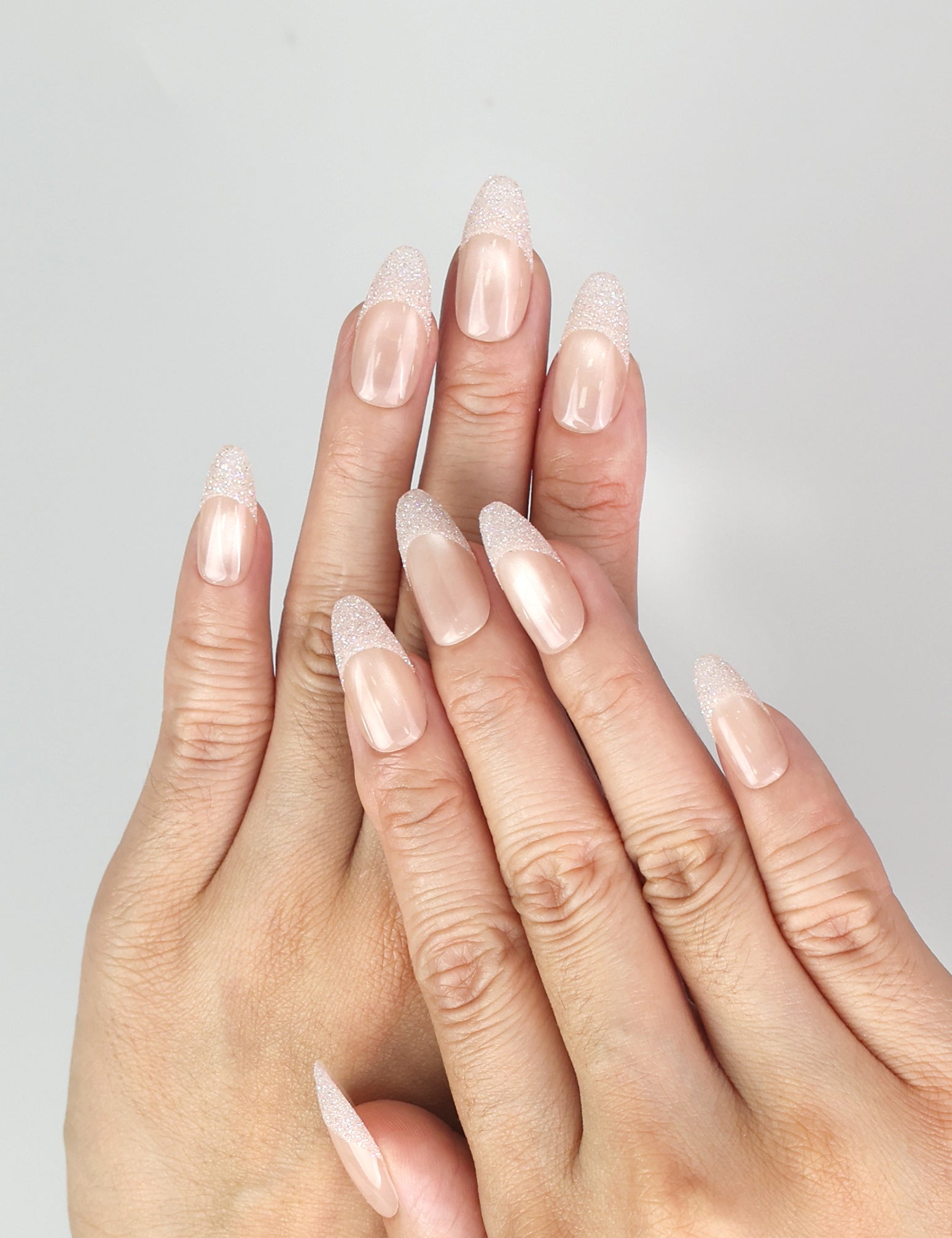 Hand wearing Naillover Crystal Whisper Singapore press on nails, showcasing soft nude gradient with subtle crystals and pearls