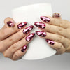 Cupid's Curve Singapore press on nails by Naillover in magenta with heart designs and rhinestones, shown holding a coffee cup