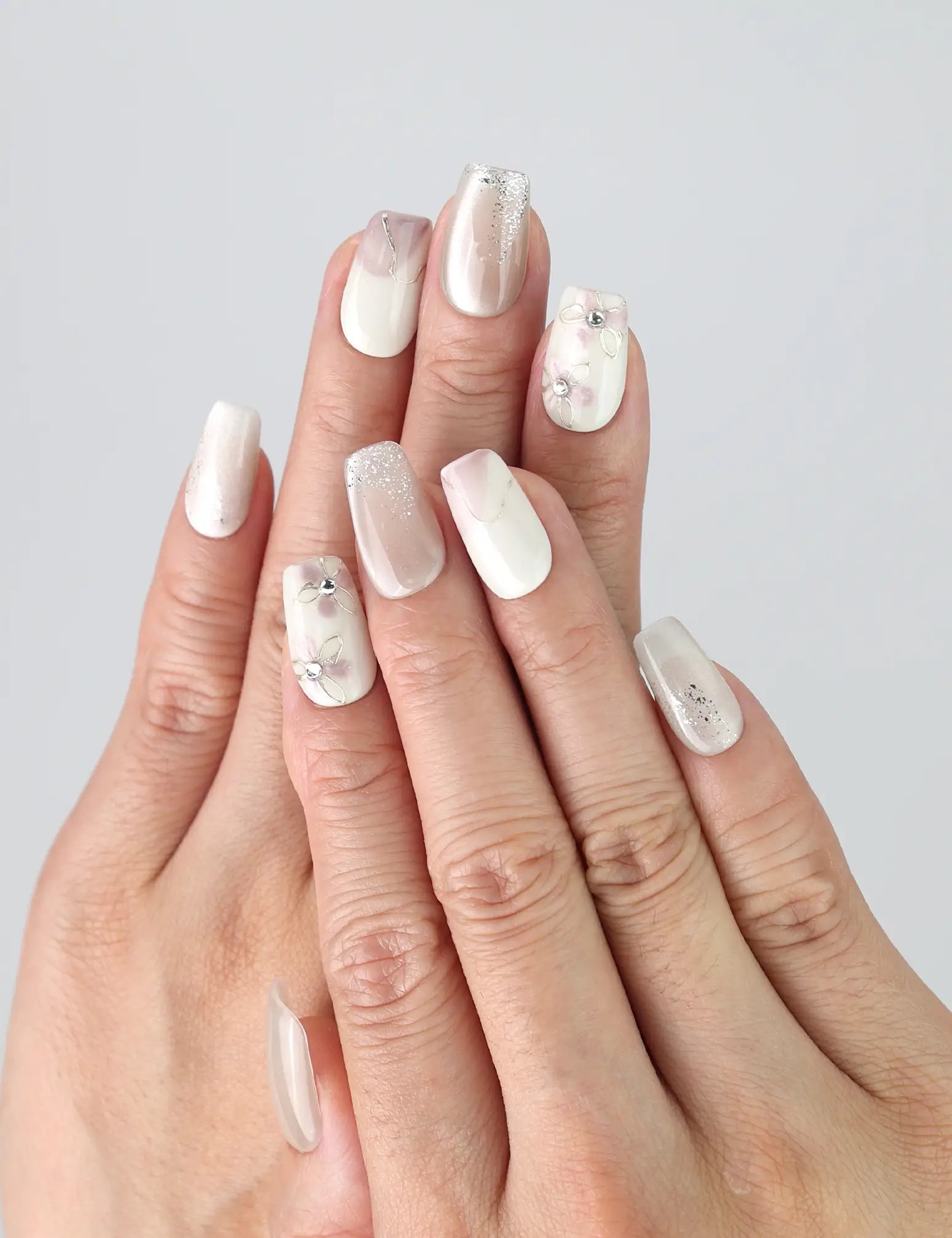 Close-up of hand wearing Flora Sheen press on nails by Naillover, showcasing pink and white floral gradient with a minimalist, 3D finish.