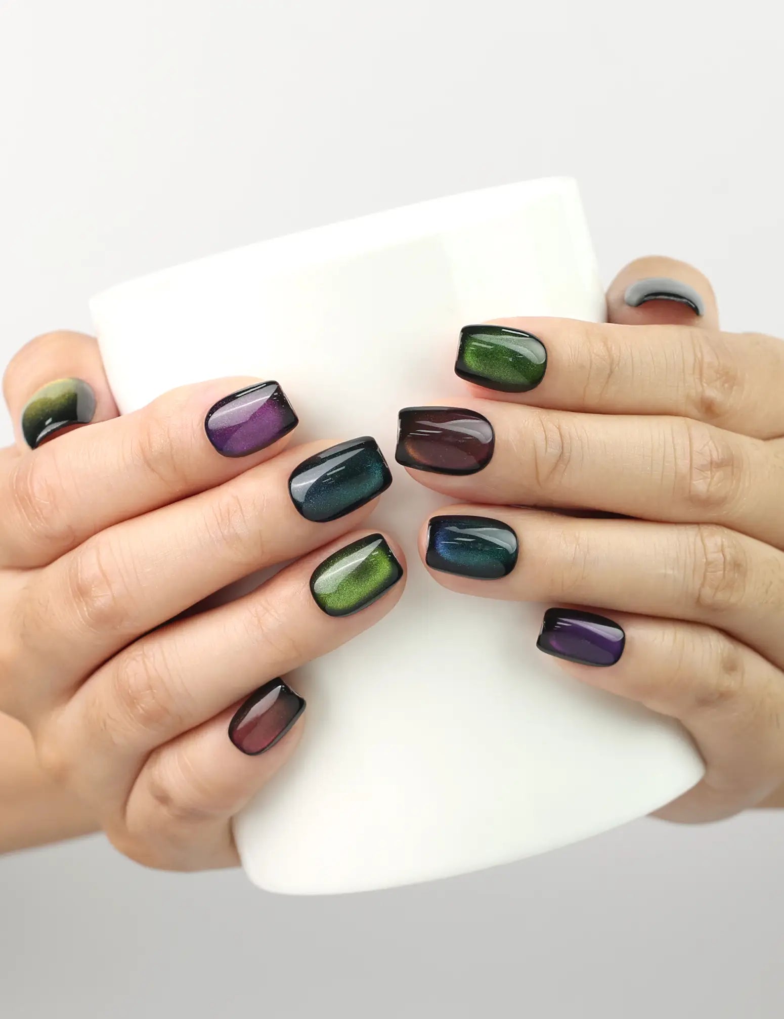 Galaxy Velvet black cat eye handmade press on nails from Singapore by Naillover, jewel tones glowing while holding a coffee cup