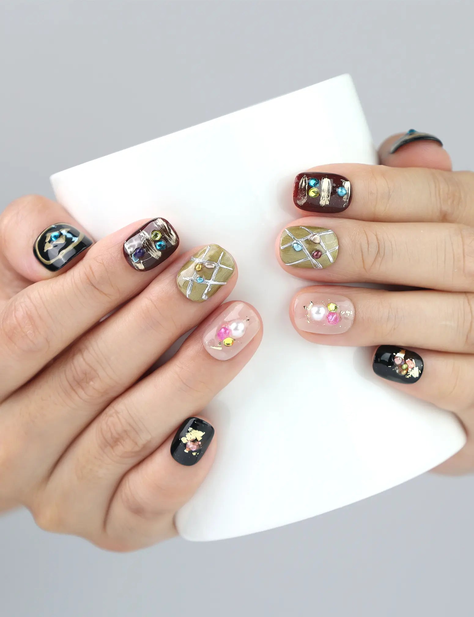 Naillover’s Gem Enchant press on nails holding a mug—black polish with glittering stars and crystals for a standout look.