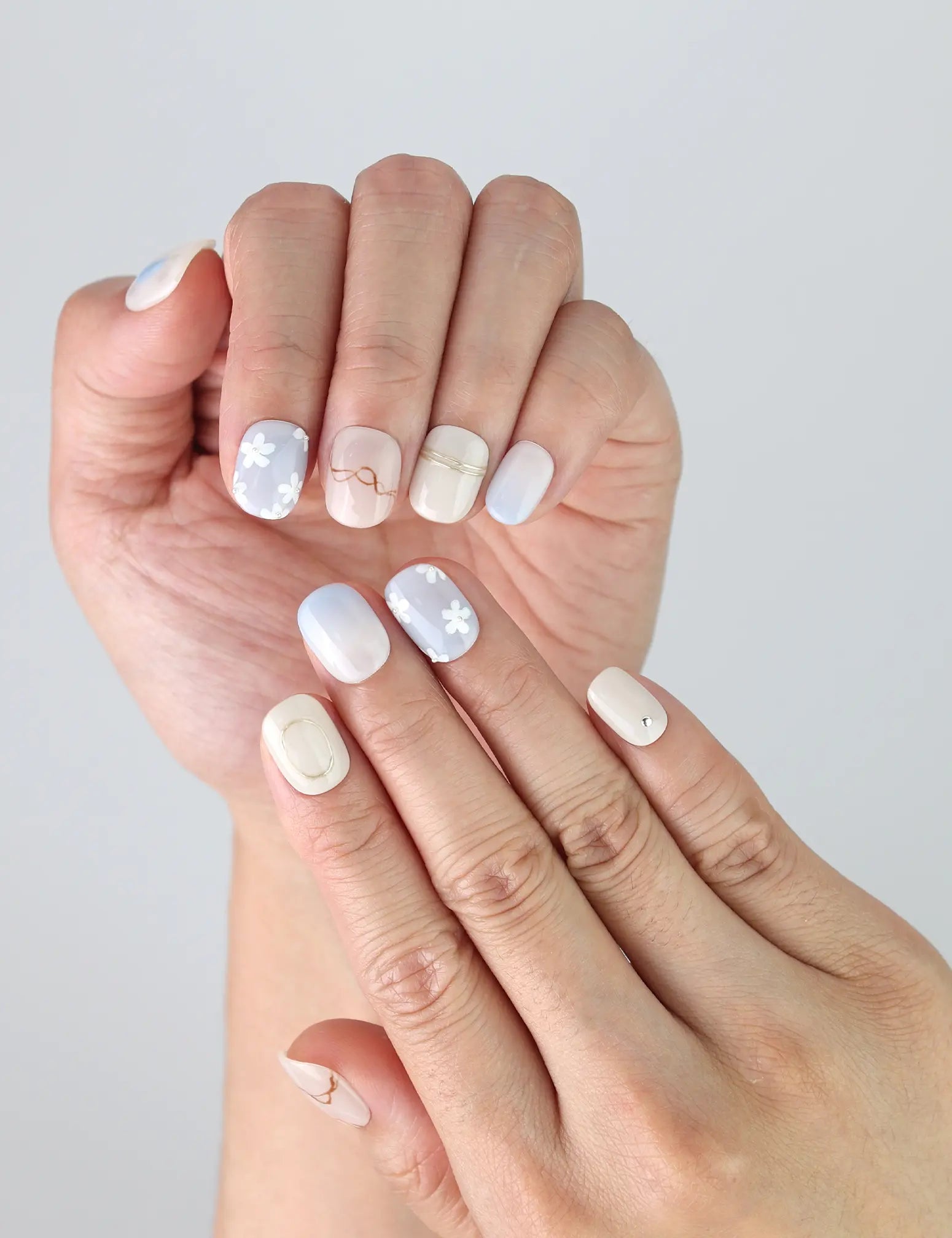 Close-up of Gentle Echo press on nails on fingers, showing simple floral design with a classic finish.