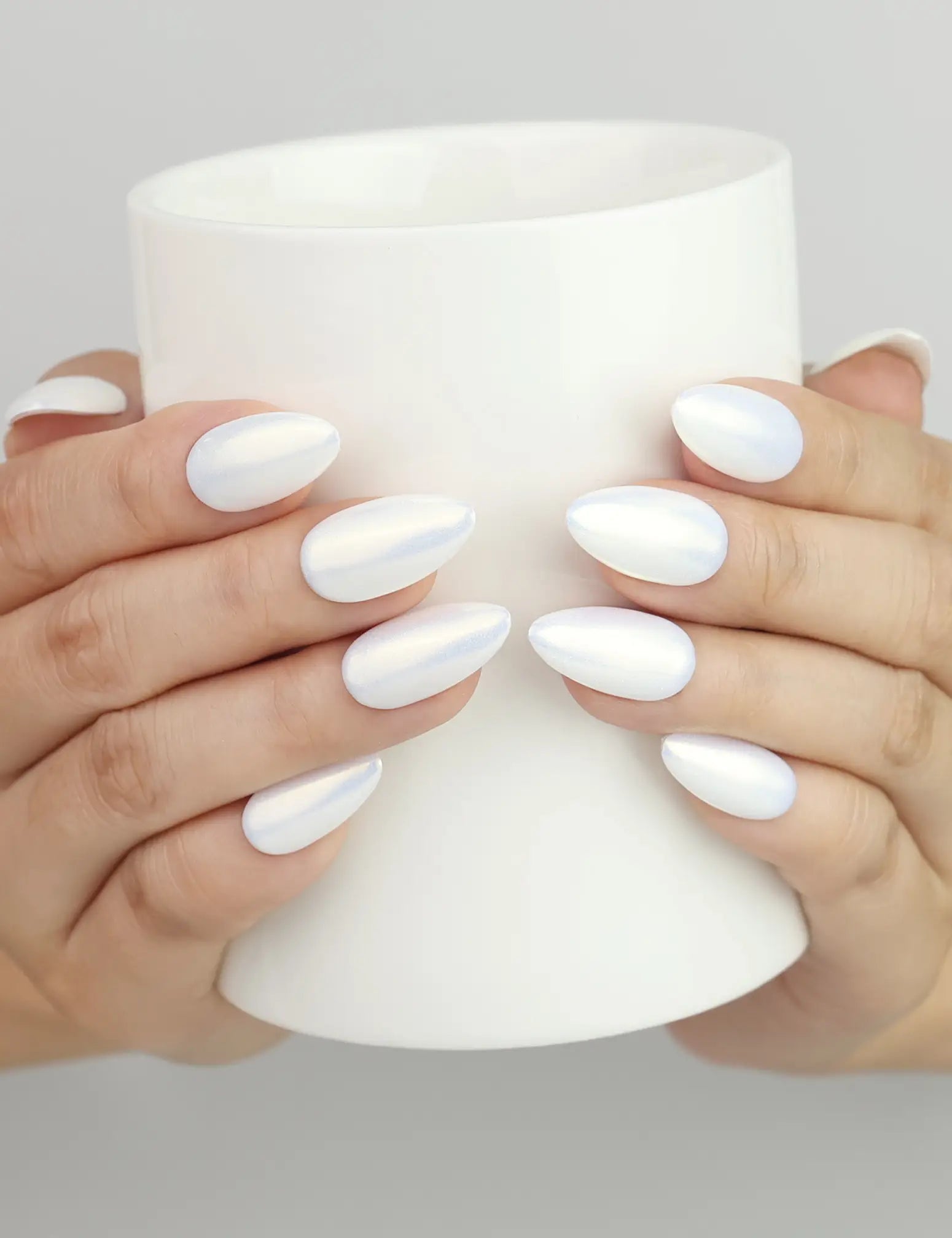 Naillover Glacial Glow handmade press on nails SG, iridescent trendy nails shown while holding a cup