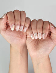 Naillover Glimmer Blossom handmade press on nails in soft pink and shimmer tones worn on model’s hand.