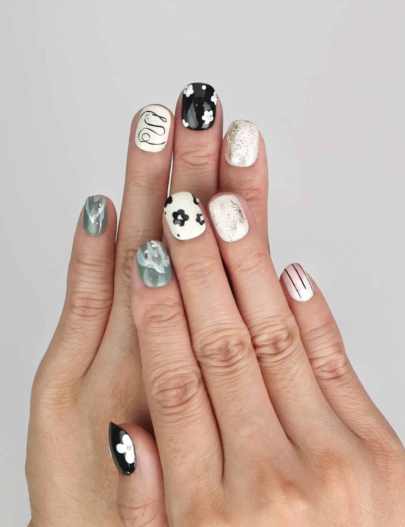 Model wearing Naillover Inky Blossoms handmade press on nails Singapore with bold black, white, and green floral art.