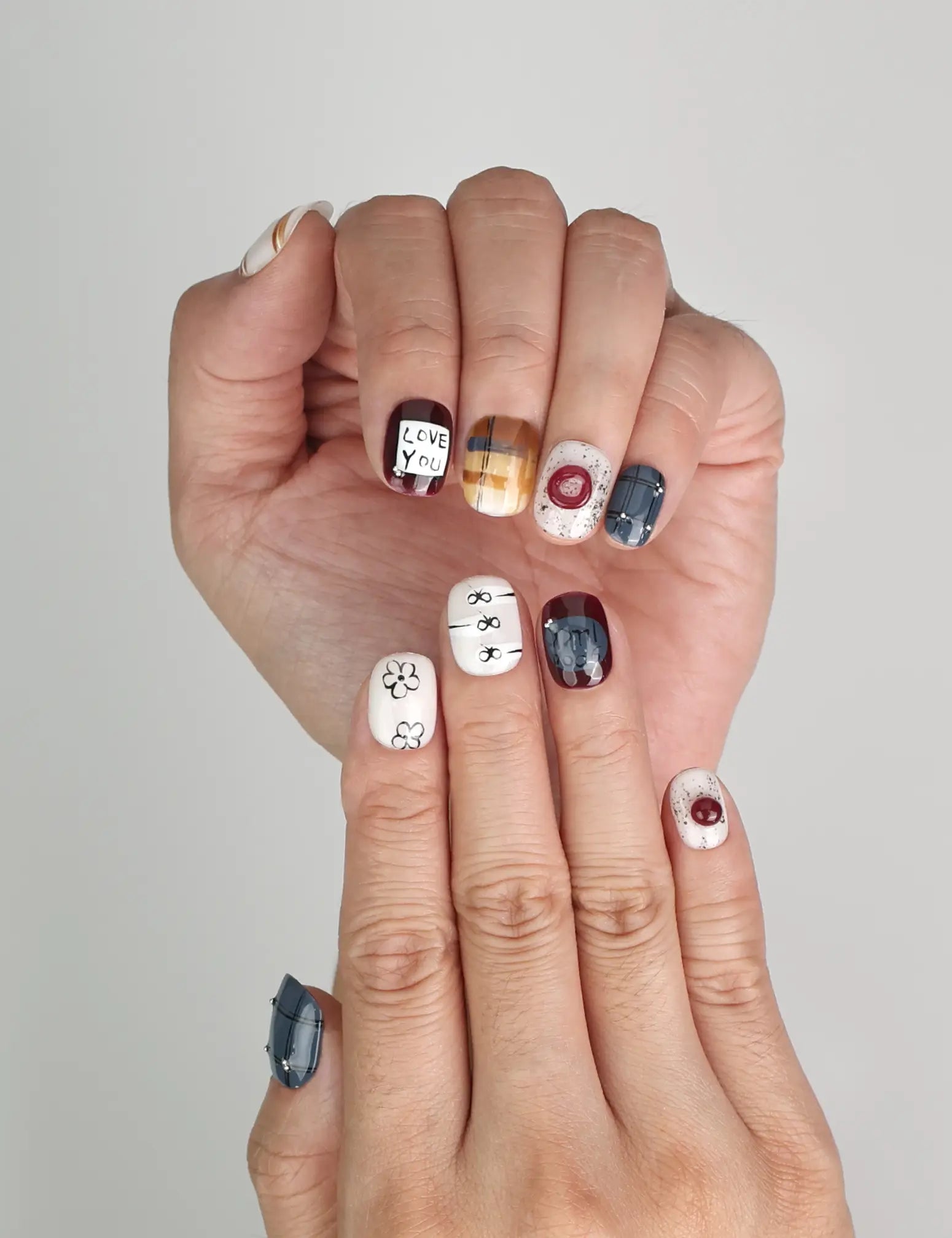 Close-up of Naillover Love Notes Singapore press on nails featuring bow and flower motifs with “LOVE YOU” design.